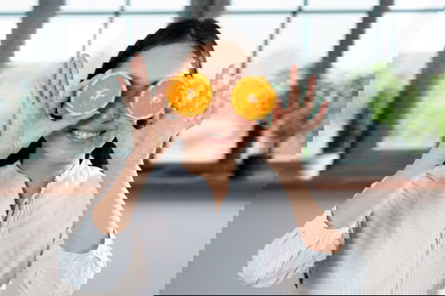 Smiling Woman Holding Slices Orange Front Her Eyes Home 23 2148076072