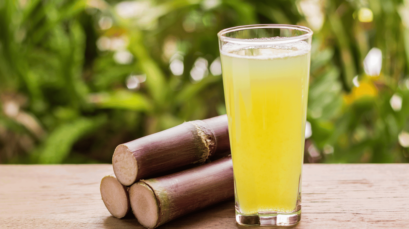 Fresh Sugarcane Juice Served In A Glass With Ice Cubes, Garnished With A Slice Of Lemon And A Bunch Of Sugarcane Stalks, Showcasing Its Natural, Refreshing Look And Health Benefits