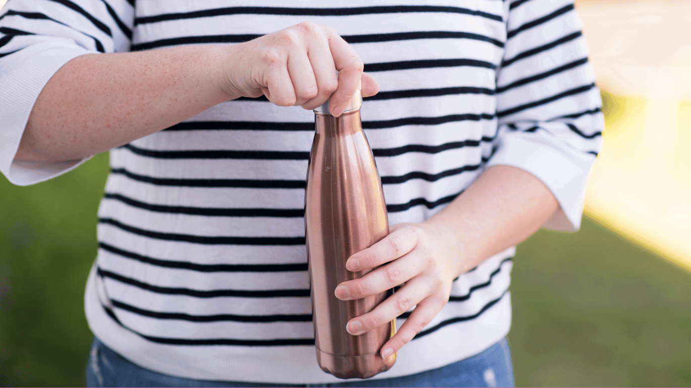 A Sleek And Stylish Copper Water Bottle Placed On A Wooden Surface, Highlighting Its Health Benefits And Ayurvedic Advantages.